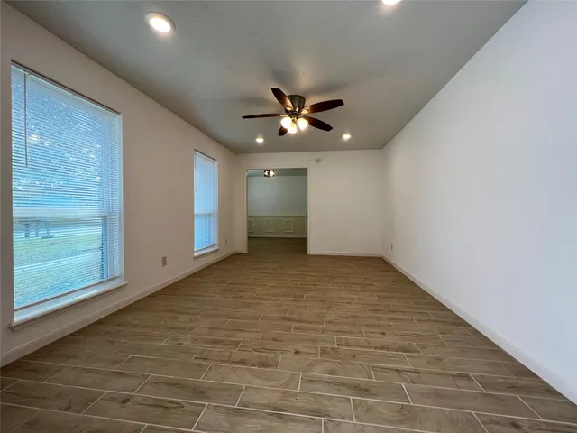 a view of an empty room with wooden floor and a fireplace