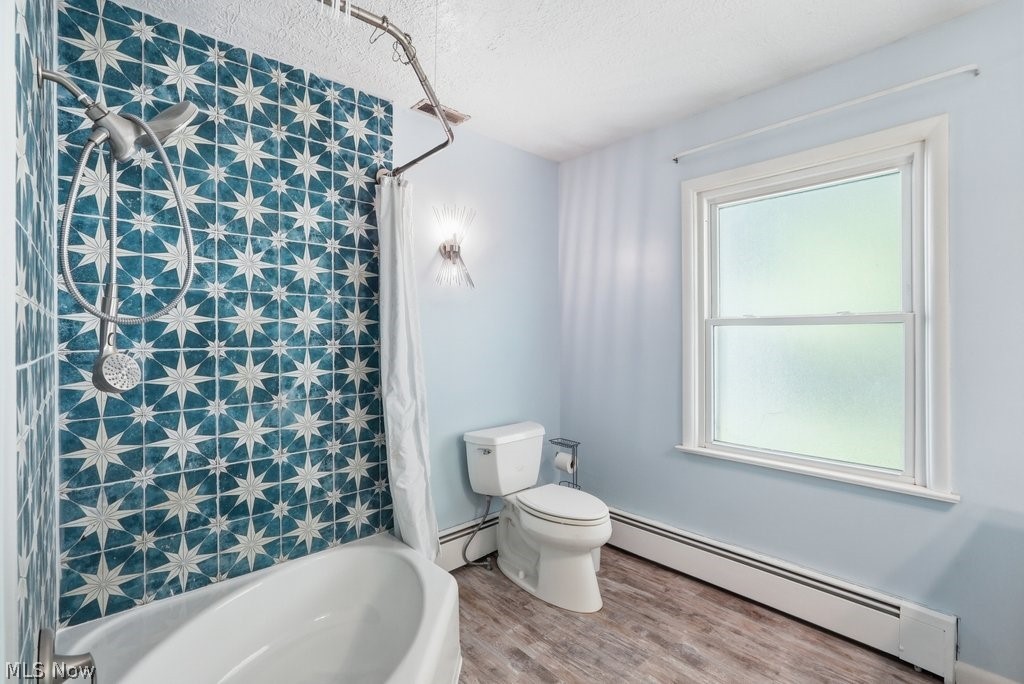 136 Pinehurst Road Munroe Falls, OH 44262 - Photo 18 of 48 Bathroom featuring patterned tile shower surround, white bathtub, wood-finish flooring, white double-hung window, and light blue wall paint