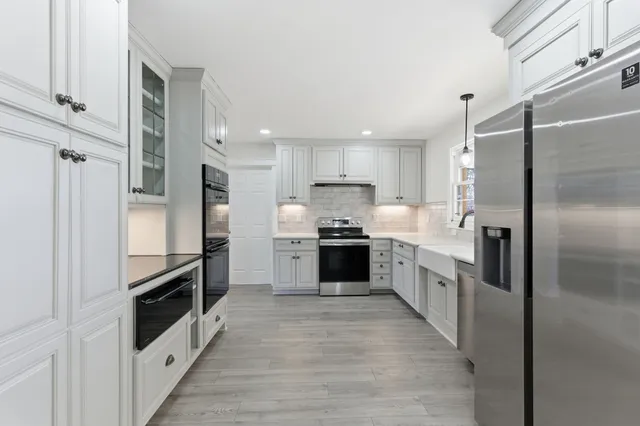 a large kitchen with a large counter top a stove a sink and a refrigerator