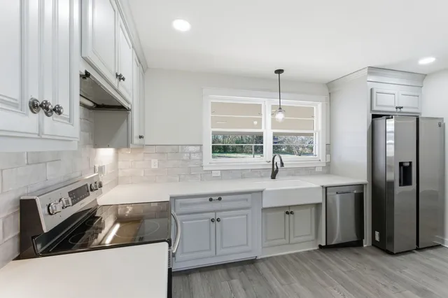 a kitchen with stainless steel appliances granite countertop a sink a stove and a refrigerator