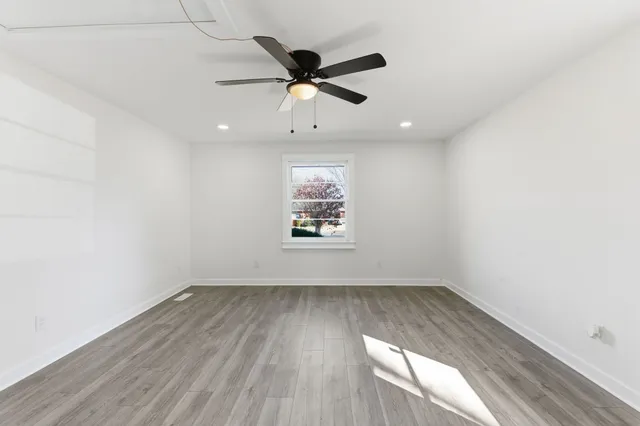 a view of empty room with wooden floor and ceiling fan