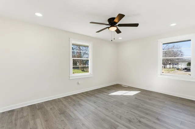a view of empty room with wooden floor and ceiling fan