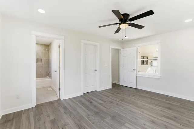 an empty room with wooden floor ceiling fan and windows