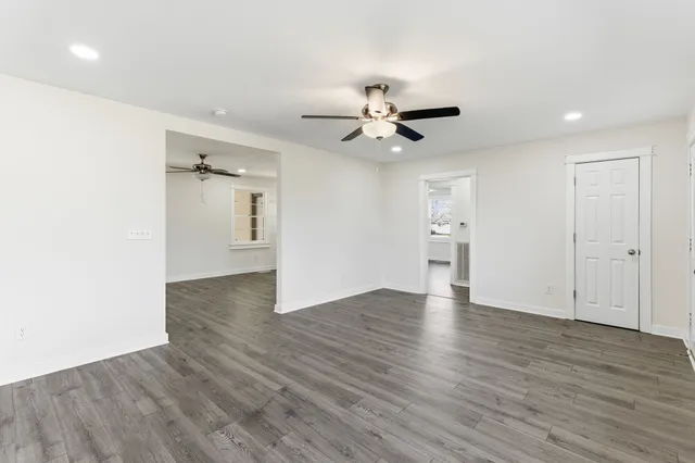 a view of an empty room with a window and wooden floor