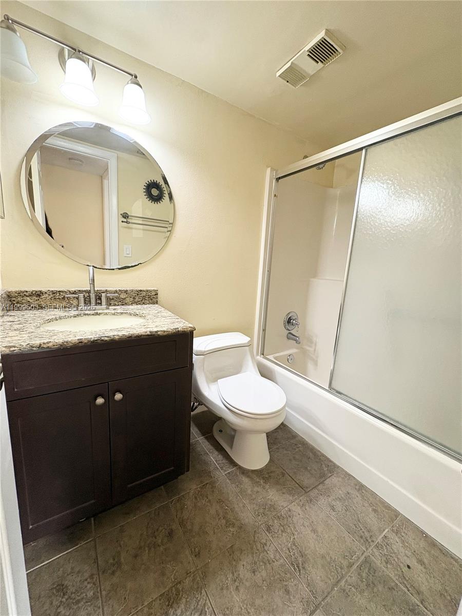 21904 Lake Forest Circle, Unit 203 Boca Raton, FL 33433 - Photo 9 of 11 a bathroom with a toilet a sink and a mirror