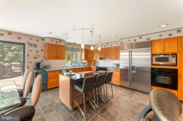 a kitchen with stainless steel appliances granite countertop a refrigerator a stove a sink a dining table and chairs with wooden floor