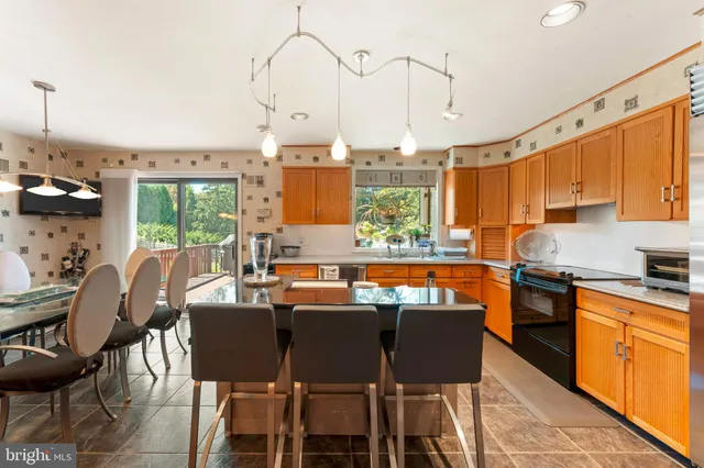 a kitchen with stainless steel appliances granite countertop a stove top oven a sink a dining table and chairs with the wooden floor