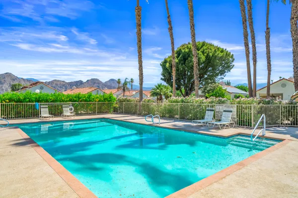 a view of a swimming pool with lawn chairs and plants