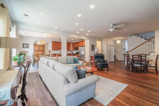a living room with furniture kitchen view and a wooden floor