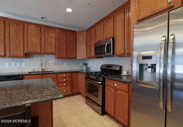 a kitchen with stainless steel appliances granite countertop a refrigerator a stove top oven a sink and dishwasher