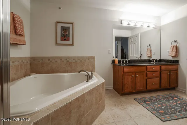 a spacious bathroom with a tub a double vanity sink and a mirror