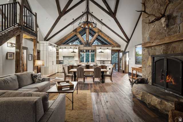 1667 West Tollgate Cyn Road Coalville, UT 84017 - Photo 27 of 61 Vaulted ceiling with exposed wood beams, stone fireplace with a substantial hearth, wood-finish flooring, custom cabinetry in the kitchen, and a dining area with pendant lighting