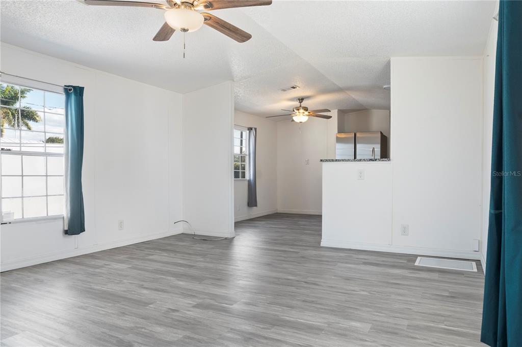 6526 Jack Street Punta Gorda, FL 33982 - Photo 5 of 19 an empty room with wooden floor chandelier fan and windows
