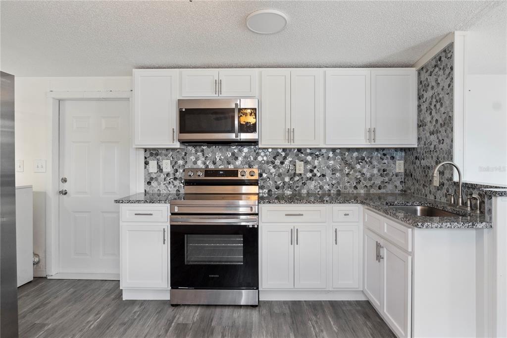 6526 Jack Street Punta Gorda, FL 33982 - Photo 7 of 19 a kitchen with white cabinets stainless steel appliances and sink