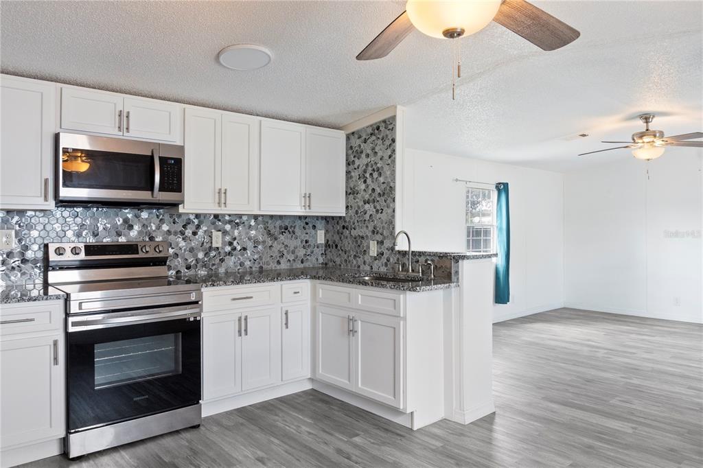 6526 Jack Street Punta Gorda, FL 33982 - Photo 8 of 19 a kitchen with cabinets stainless steel appliances a sink and wooden floor