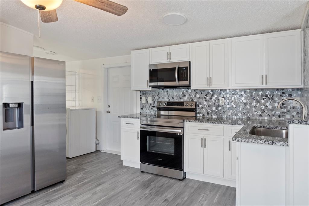 6526 Jack Street Punta Gorda, FL 33982 - Photo 9 of 19 a kitchen with stainless steel appliances a stove a sink and a microwave