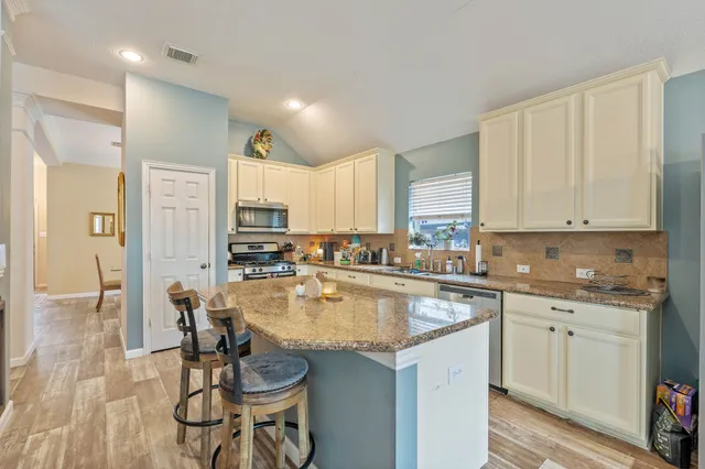 a kitchen with stainless steel appliances granite countertop a table chairs sink refrigerator and cabinets