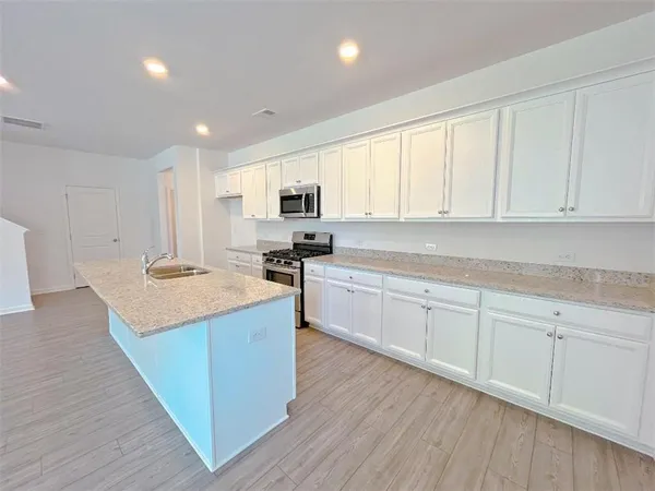 a kitchen with stainless steel appliances granite countertop a sink a stove and cabinets