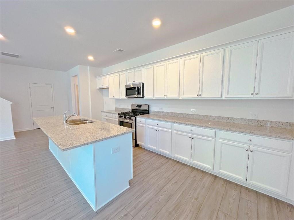 117 Goshawk Street Braselton, GA 30517 - Photo 8 of 28 a kitchen with stainless steel appliances granite countertop a sink a stove and cabinets