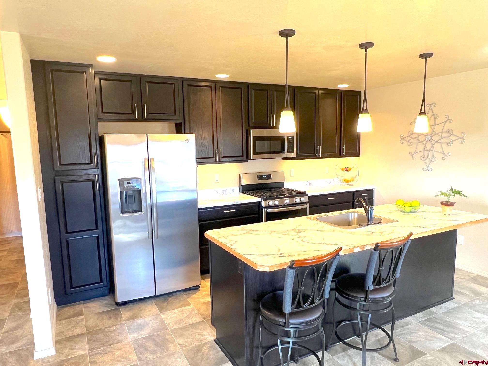 930 Bluffs Boulevard Cortez, CO 81321 - Photo 10 of 28 a kitchen with stainless steel appliances granite countertop a table chairs and refrigerator
