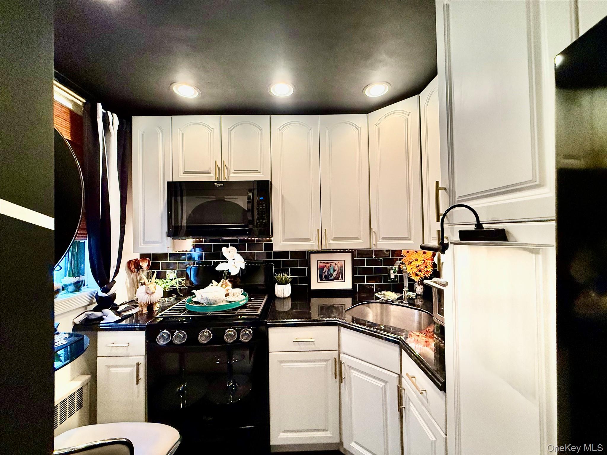 112-25 34th Avenue, Unit 2D Queens, NY 11368 - Photo 12 of 37 Kitchen with black appliances, tasteful backsplash, white cabinets, dark stone countertops, and recessed lighting