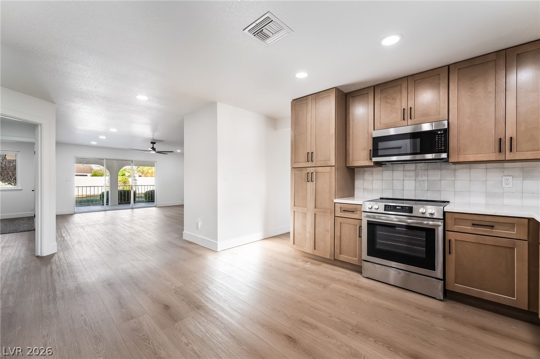 429 Crestway Road Henderson, NV 89015 - Photo 20 of 56 A contemporary kitchen and living area featuring sleek cabinetry and light-toned flooring.