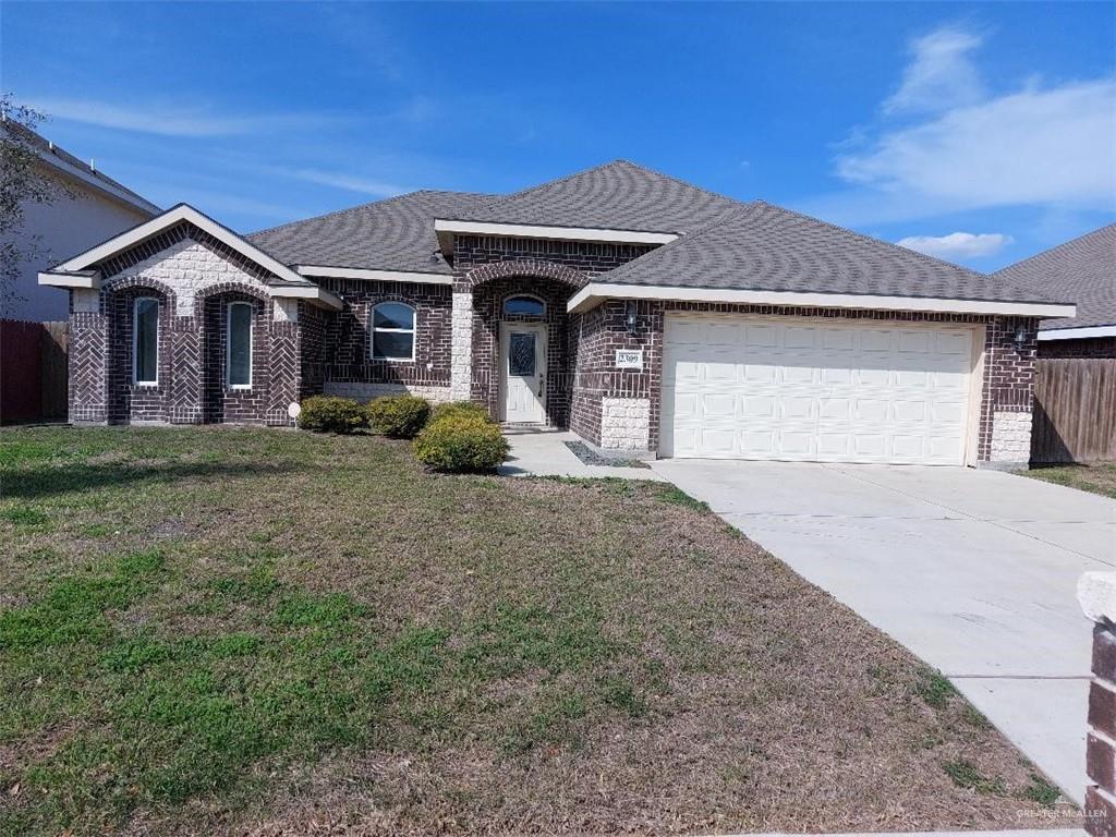 View of front facade with a garage, brick siding, driveway, roof with shingles, and a front lawn