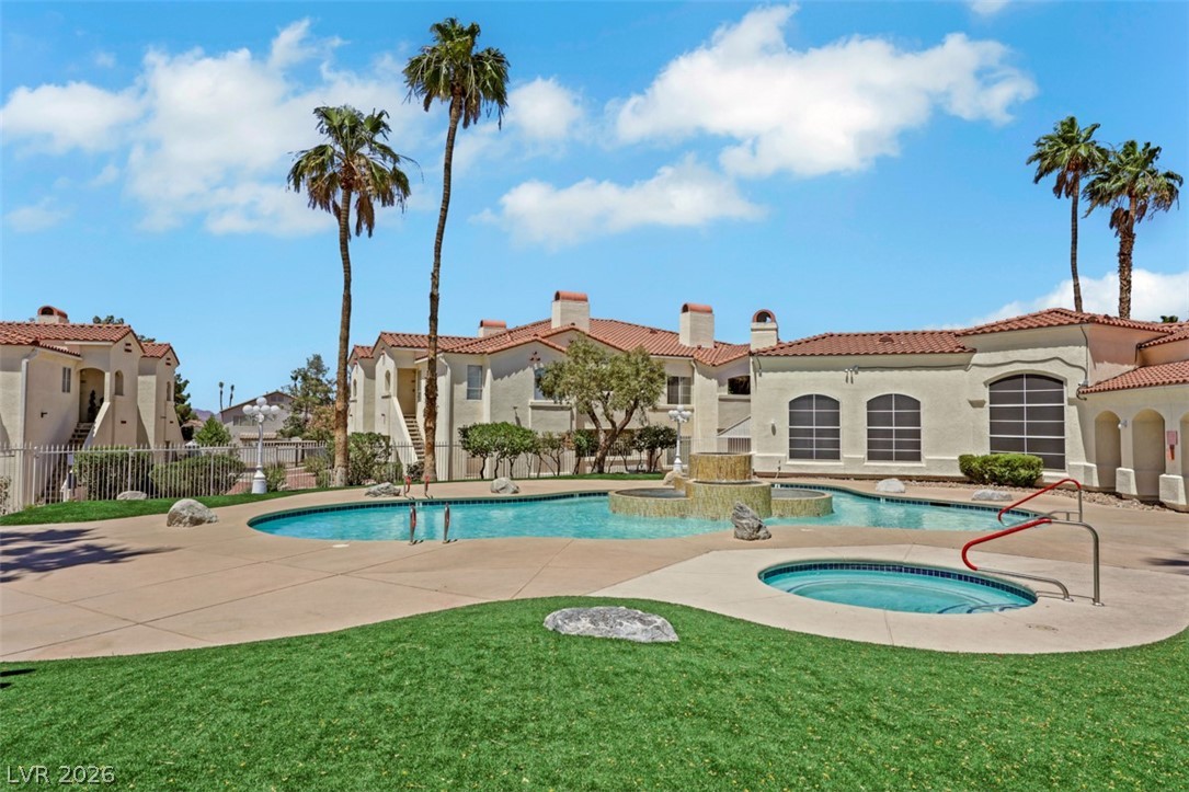 698 South Racetrack Road, Unit 1614 Henderson, NV 89015 - Photo 20 of 35 A refreshing pool and spa area with a fountain, nestled amidst tropical landscaping and a tiled roof building.