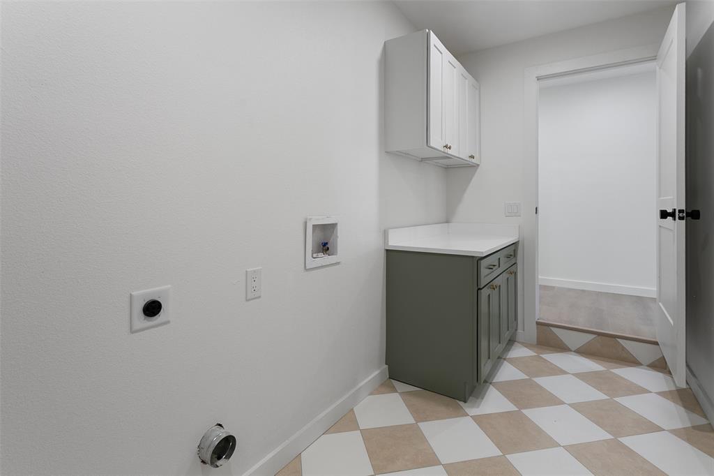 1346 South Reno Road Springtown, TX 76082 - Photo 17 of 24 Laundry area featuring checkerboard tile flooring, a built-in base cabinet with a light-colored countertop, and a white upper cabinet