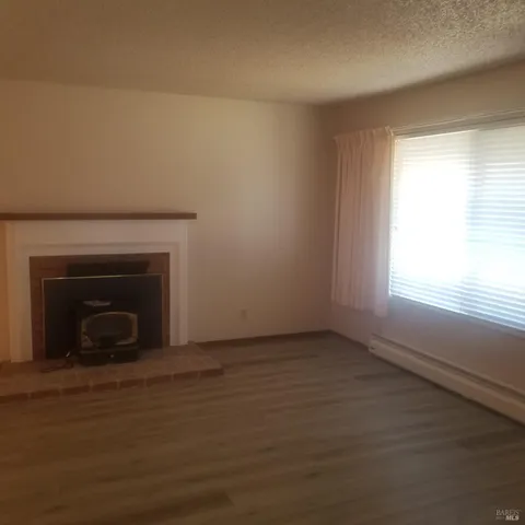 a view of empty room with wooden floor and a fireplace