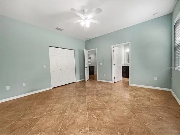 an empty room with closet and a ceiling fan