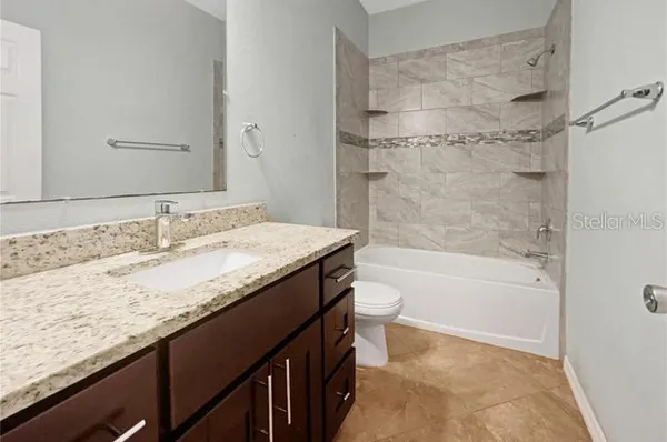 a bathroom with a granite countertop sink a toilet and bathtub