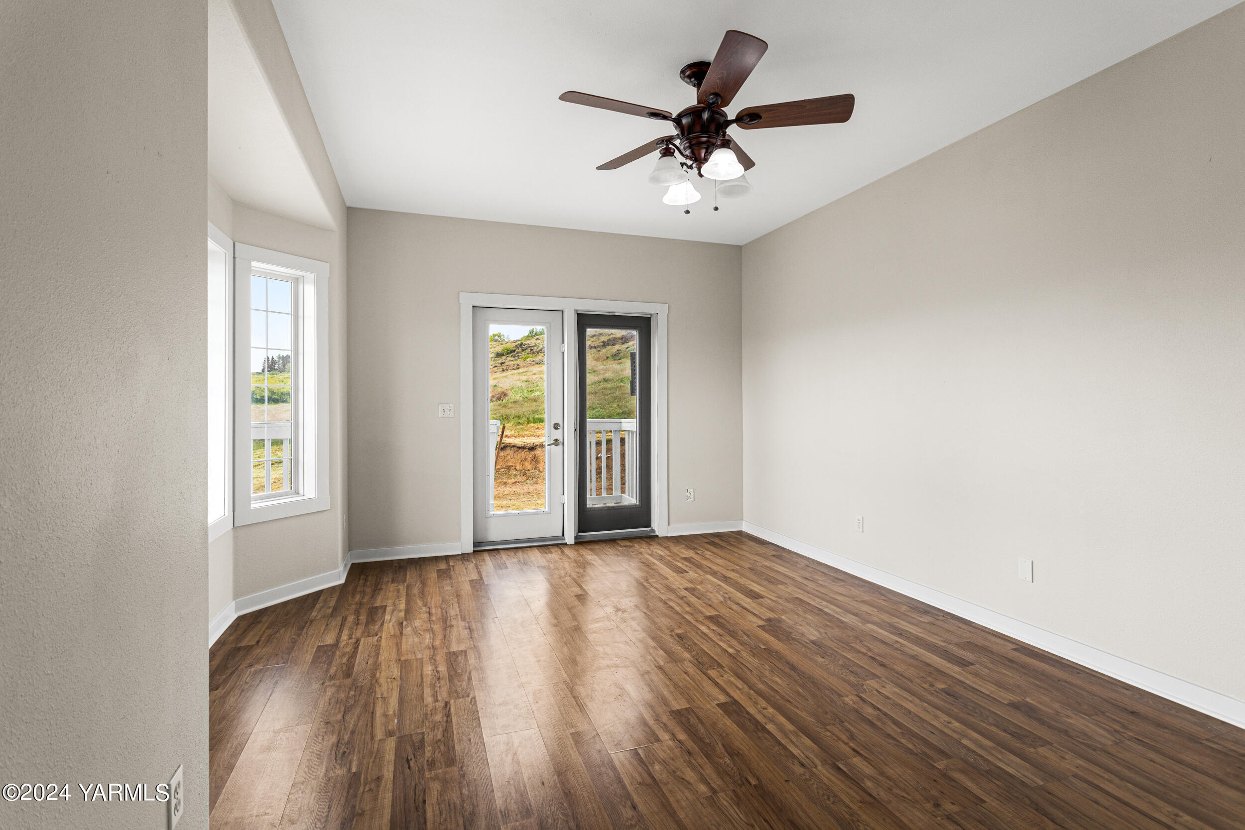 633 Hancock Road Cowiche, WA 98923 - Photo 18 of 53 an empty room with wooden floor chandelier fan and windows