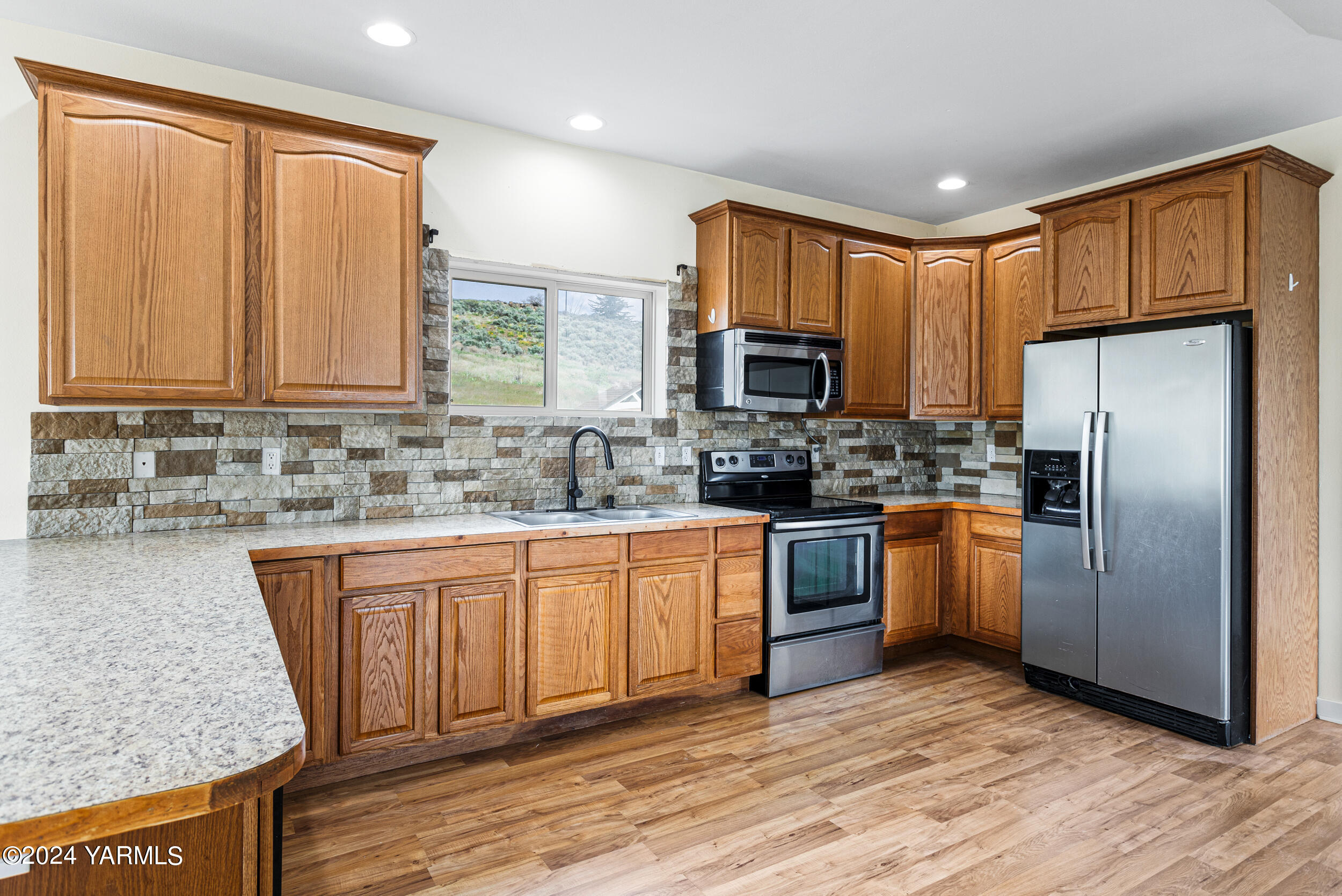 633 Hancock Road Cowiche, WA 98923 - Photo 26 of 53 a kitchen with stainless steel appliances granite countertop a refrigerator a sink dishwasher and wooden cabinets with wooden floor