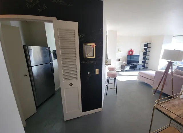 a living room with furniture and a refrigerator