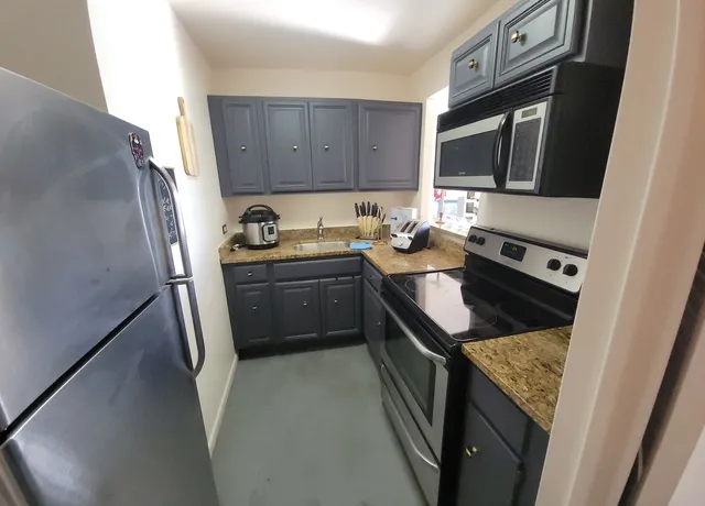 a kitchen with granite countertop a sink stove and microwave