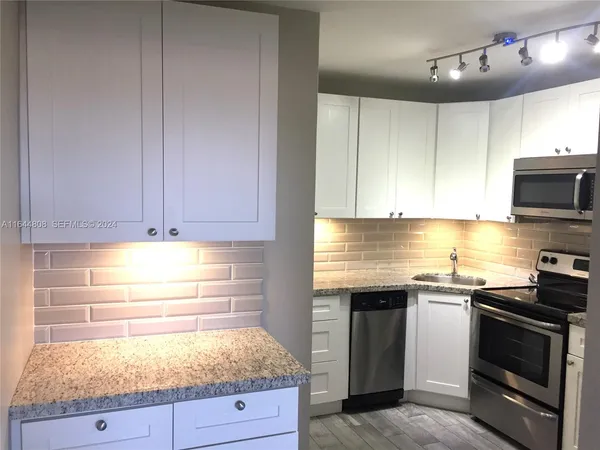 a kitchen with granite countertop stainless steel appliances a stove microwave and cabinets