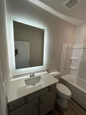 a bathroom with a sink a toilet a mirror and shower