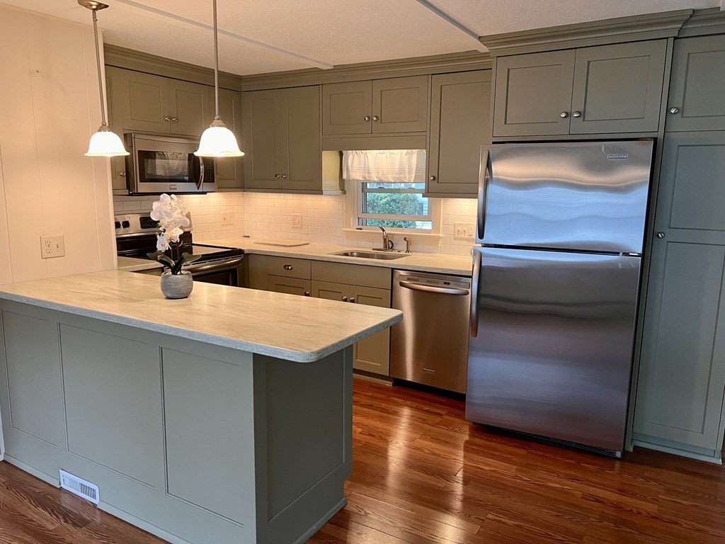 25 St James Circle Hudson, MA 01749 - Photo 4 of 15 a kitchen with kitchen island granite countertop a sink a counter space and cabinets