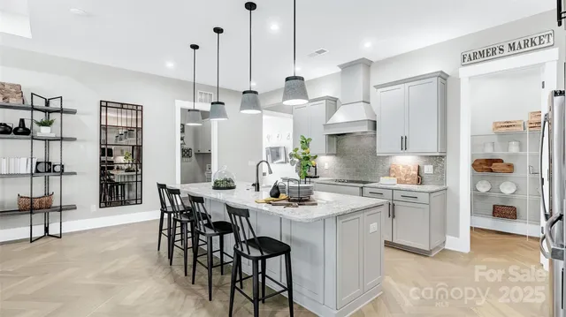 a kitchen with stainless steel appliances kitchen island granite countertop a table chairs and a refrigerator