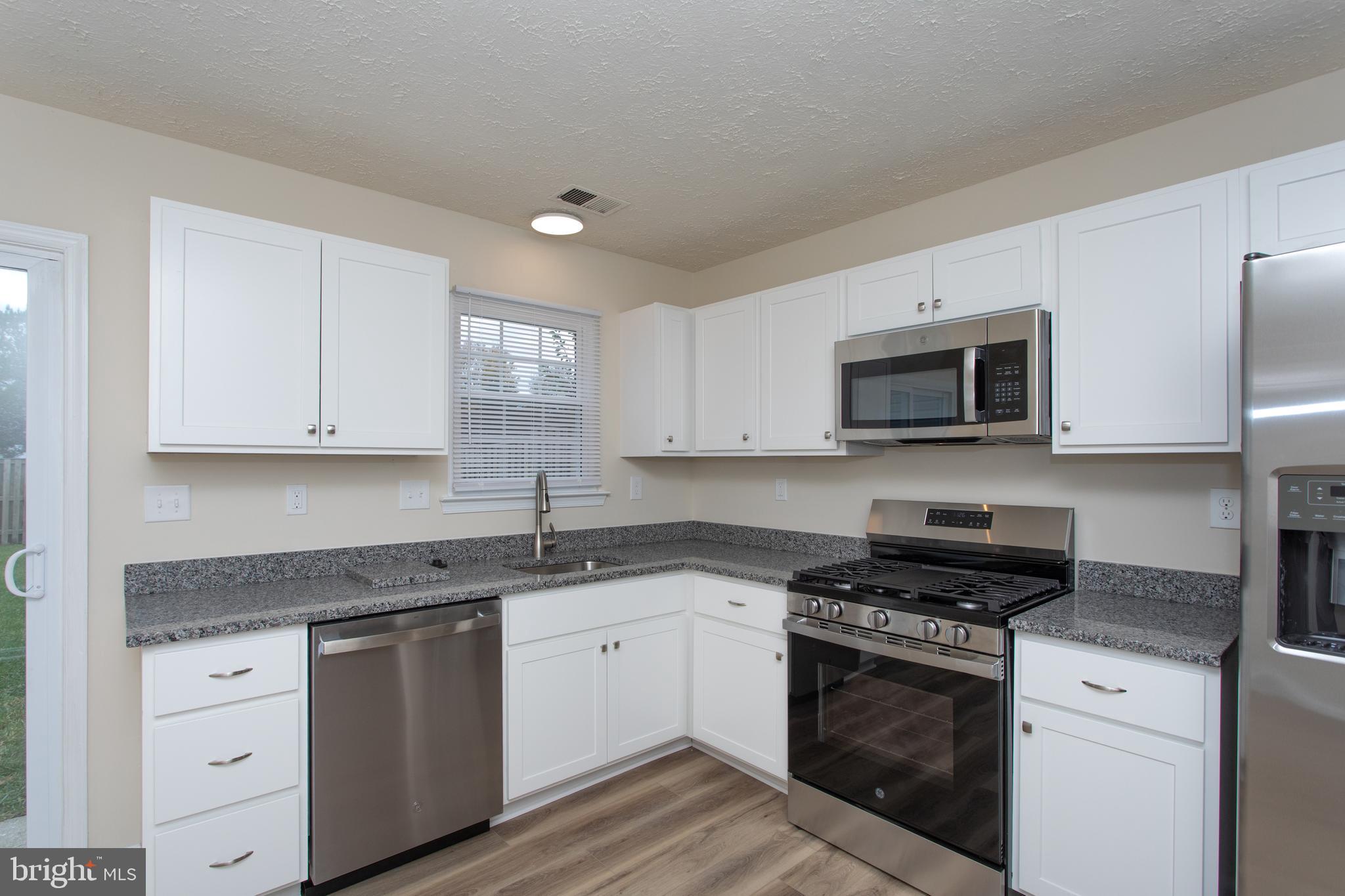 5704 Springfish Place Waldorf, MD 20603 - Photo 14 of 38 a kitchen with granite countertop a sink cabinets and stainless steel appliances