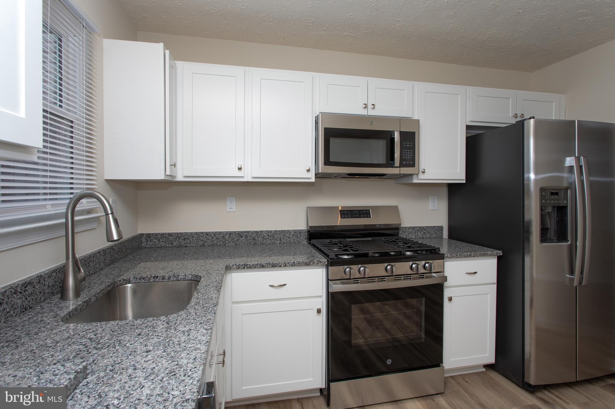 5704 Springfish Place Waldorf, MD 20603 - Photo 15 of 38 a kitchen with granite countertop a sink stove and refrigerator