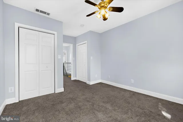 an empty room with closet and a chandelier fan