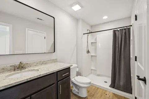 a bathroom with a granite countertop sink toilet and shower