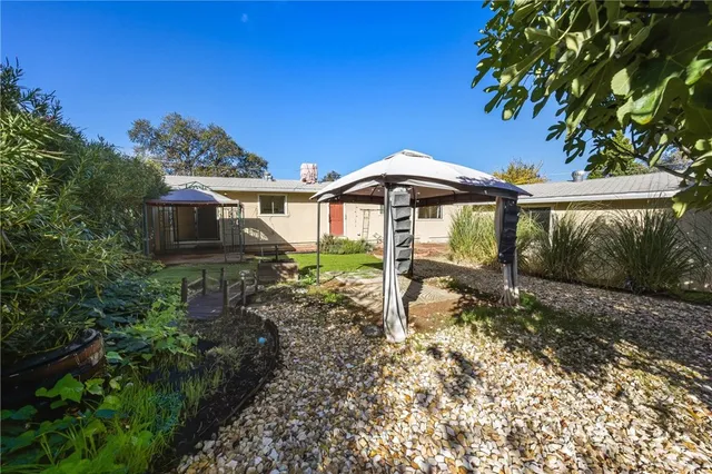 a backyard of a house with table and chairs under an umbrella