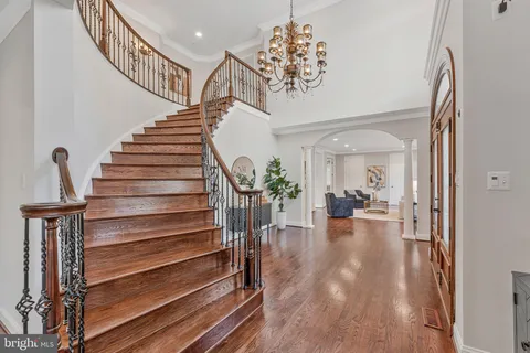 a dining room with wooden floor a chandelier a wooden table and chairs