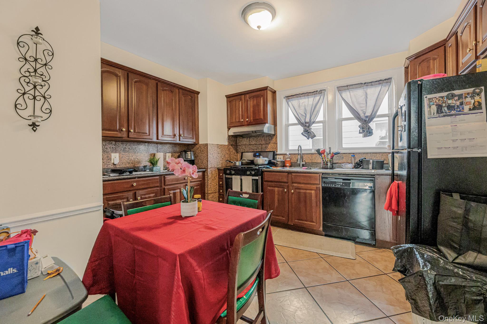 168 Stephenson Boulevard New Rochelle, NY 10801 - Photo 18 of 21 Kitchen featuring black appliances, decorative backsplash, under cabinet range hood, and light tile patterned flooring