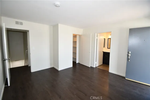 an empty room with wooden floor & windows