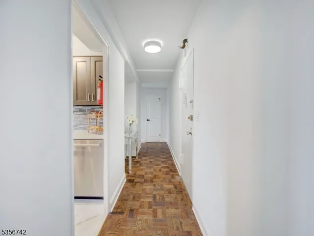 a hallway with white walls and wooden floor