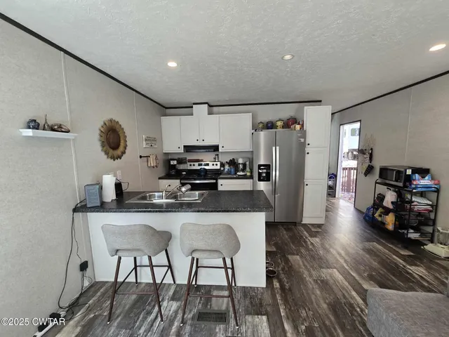 a kitchen with stainless steel appliances granite countertop a sink refrigerator and cabinets